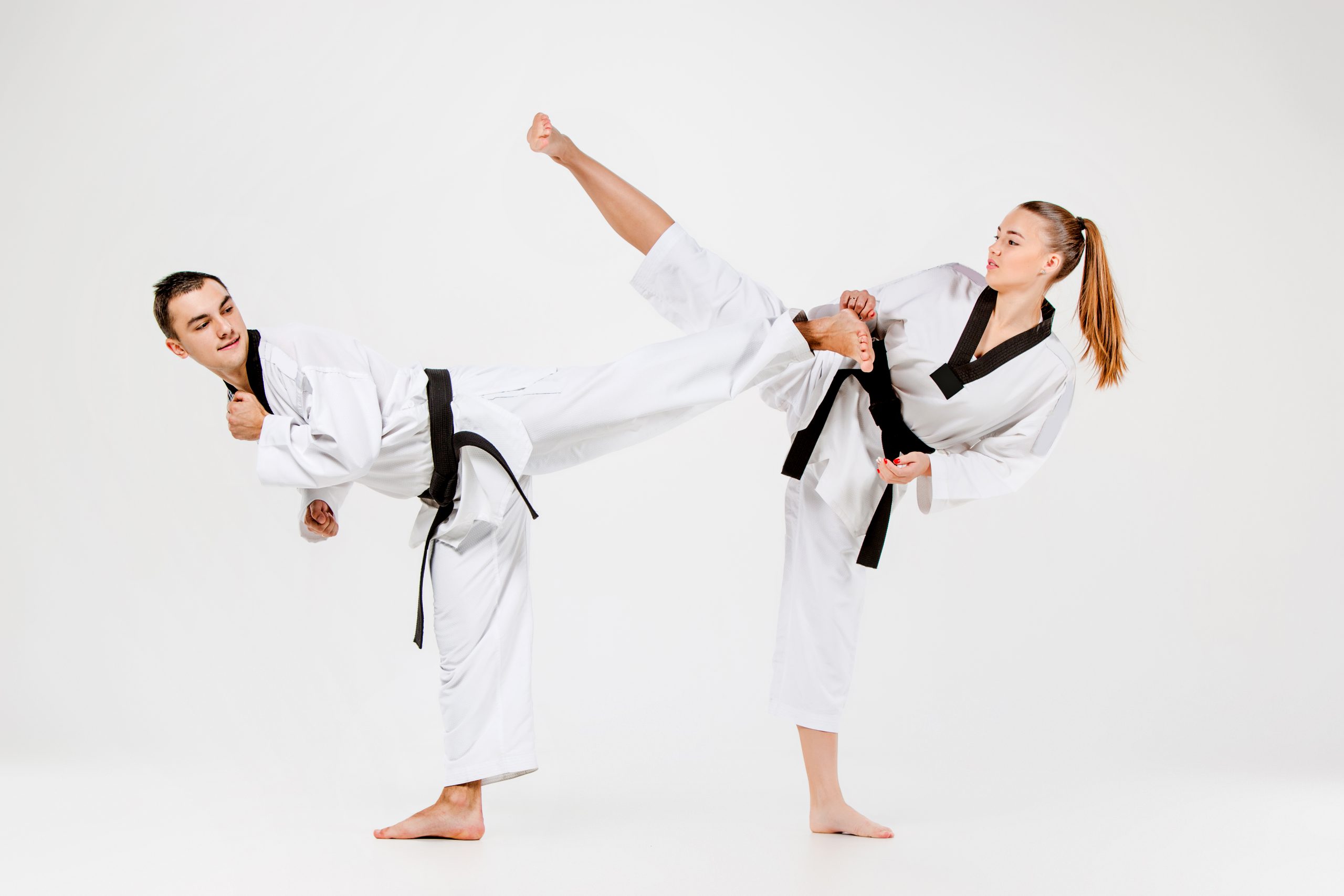 The karate girl and boy in white kimono and black belt training karate over gray background.